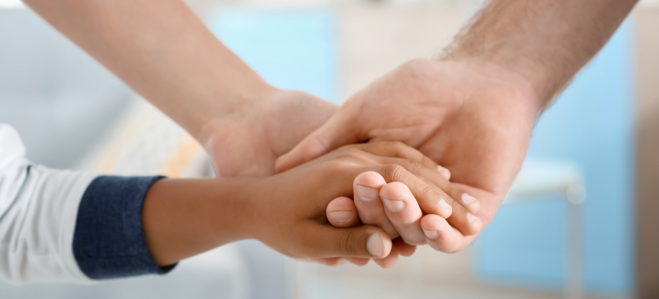 A family holds hands, symbolizing the moments of connection that museum visits make possilbe