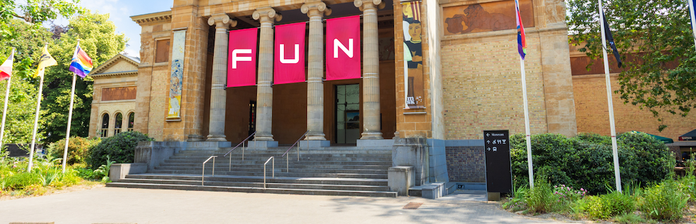 A museum building with columns and digitally-altered banners displayed that spell out FUN.